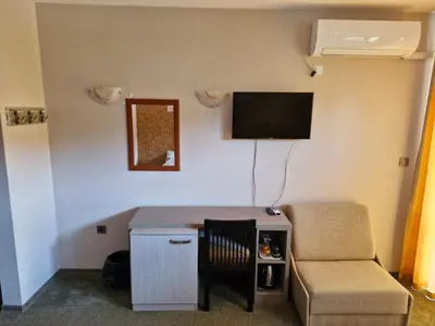 a living room with a table and a chair and a tv at Family hotel Favourite in Obzor