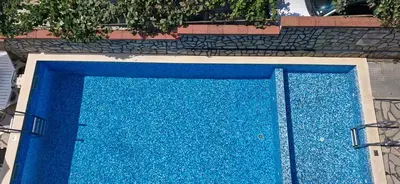 a blue swimming pool in front of a building at Family hotel Favourite in Obzor