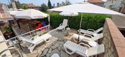 a group of white chairs and an umbrella at Family hotel Favourite in Obzor