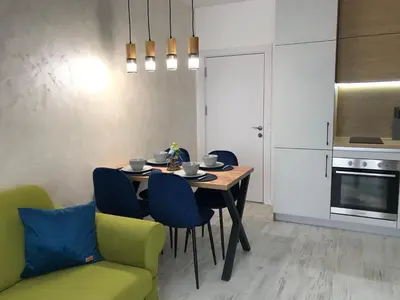 a kitchen with a dining room table and blue chairs at Аpartment Bella Vista in Obzor