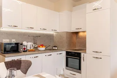a kitchen with white cabinets and a table with chairs at Summertime in Varna South Bay Beach Residence in Varna City