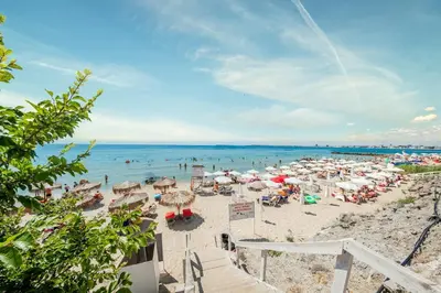 a beach with many umbrellas and people in the water at Premier Fort Beach Luxury in Sveti Vlas