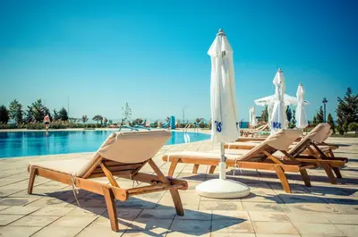 three lounge chairs and an umbrella next to a pool at Premier Fort Beach Luxury in Sveti Vlas