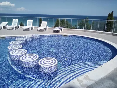 a swimming pool with chairs and the ocean in the background at Silver Beach A98 in Byala