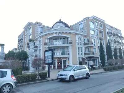 two cars parked in front of a large building at Messembria Palace Bulgaria in Sunny Beach