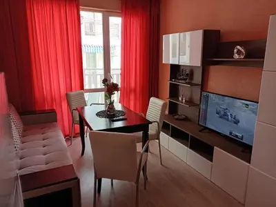 a living room with a dining room table and a television at Апартамент Spirit in Nesebar
