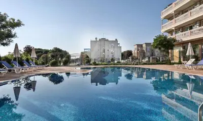 a large swimming pool with chairs and a building at Студио Симона 2 - първа линия море in Lozenets