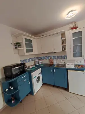 a kitchen with blue cabinets and a washing machine at Апартамент - студио в кв Сарафово с морски изглед in Burgas City