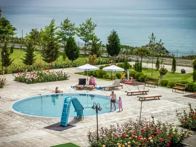 a pool with a slide and people standing around it at Prestige Fort Beach - Premium apartments in Sveti Vlas