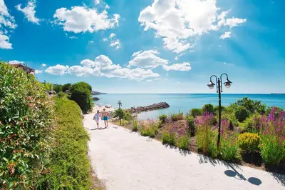 people walking down a path next to the ocean at Prestige Fort Beach - Premium apartments in Sveti Vlas
