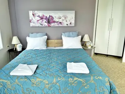 a bedroom with a blue bed with two white towels at Апартамент Компас in Burgas City