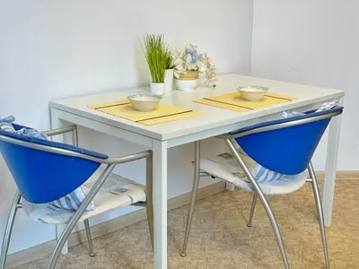 a white table with two blue chairs and plants at Апартамент Компас in Burgas City