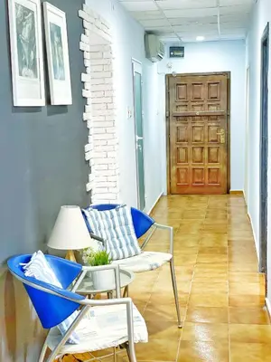 a room with a blue chair and a table and a door at Апартамент Компас in Burgas City
