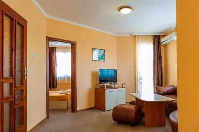 a room with a living room with a tv and a table at Хотел Бриз in Kiten