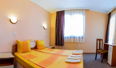 a bedroom with a bed with yellow pillows and a window at Хотел Бриз in Kiten