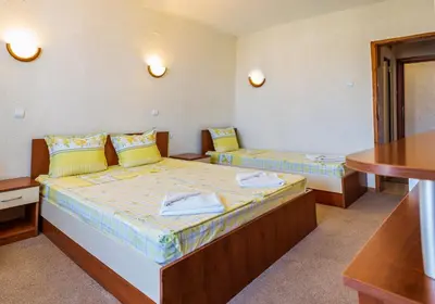 a room with two beds and a table at Хотел Бриз in Kiten