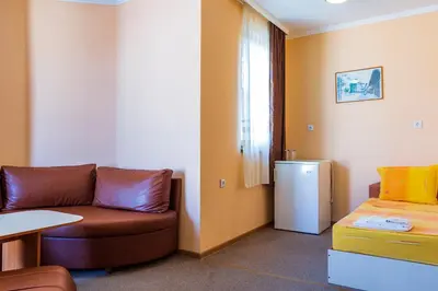 a room with a couch and a table and a refrigerator at Хотел Бриз in Kiten