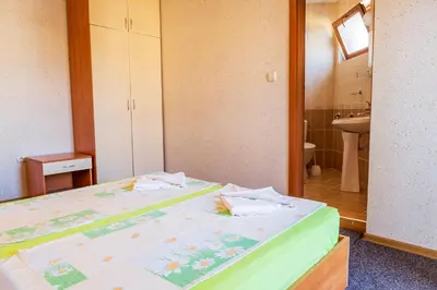 a room with two beds and a bathroom with a sink at Хотел Бриз in Kiten