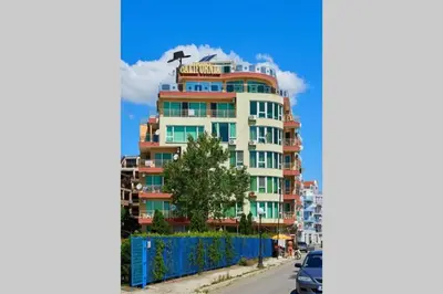 a tall building with a blue fence in front of it at Апартамент Диана in Pomorie