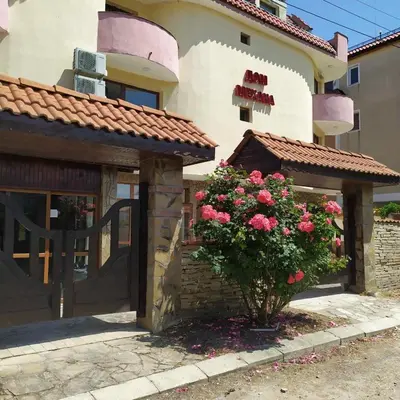 a building with a gate and a bush with pink flowers at Къща за гости Валена град Черноморец in Chernomorets