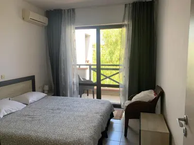 a bedroom with a bed and a view of a balcony at Apartment at St. Nicholas Complex-Igora in Chernomorets