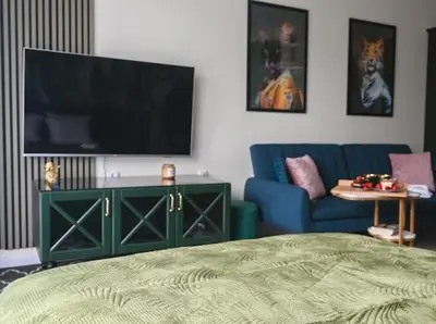 a living room with a tv and a blue couch at Nessebar Fort Club - Prestige Apartments in Sunny Beach