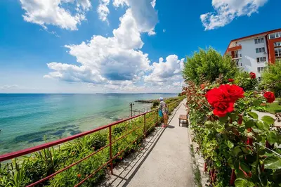 a person standing on a walkway next to the ocean at Grand Resort - Sea Viev and Premium Apartments in Sveti Vlas
