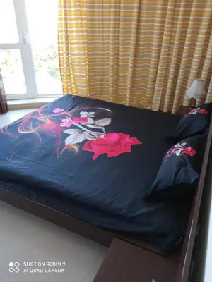 a bed with a blue comforter with flowers on it at Студио in Lozenets