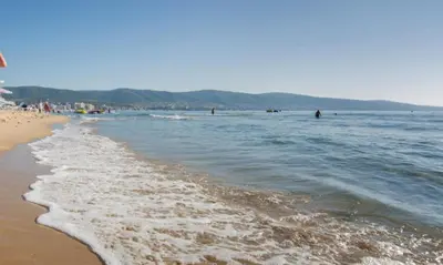 a beach with people walking in the water at ANITA B16 Studio Sunny Beach in Sunny Beach