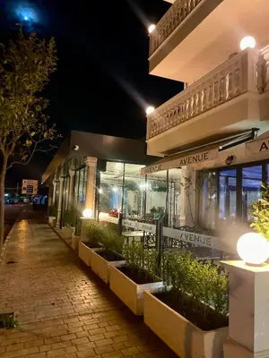 a building with plants in front of it at night at Hotel AVENUE in Ravda