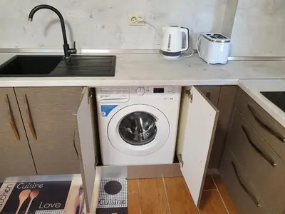 a kitchen with a washing machine under a counter at Апартамент За Гости ,,1В-15