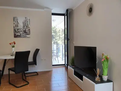 a living room with a television and a table at Апартамент За Гости ,,1В-15