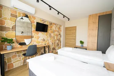 two beds in a room with a stone wall at Хотел Камъните in Burgas City