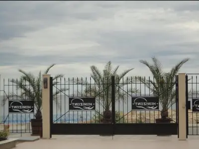 a gate with palm trees in front of the ocean at Менада Хоризонт Апартаменти in Sozopol
