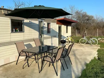 a table and chairs with an umbrella on a patio at Caravans 10 min to Tsonevo Lake & 35 min to Black Sea in Tsonevo