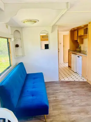 a blue couch in a room with a kitchen at Caravans 10 min to Tsonevo Lake & 35 min to Black Sea in Tsonevo
