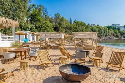 a beach with chairs and tables and a fire pit at Captain's Island Deluxe in Chernomorets