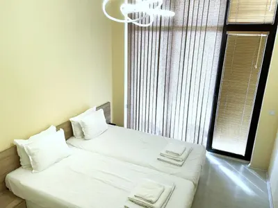 a bedroom with two beds with white sheets and a window at Private apartments Stamopolu lux in Primorsko