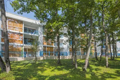 an apartment building with trees in front of it at Hotel Forest Beach in Primorsko