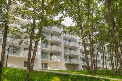 an apartment building with trees in the foreground at Hotel Forest Beach in Primorsko