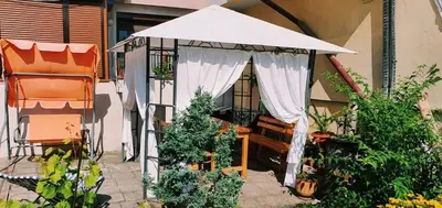 a gazebo with a white canopy and some plants at Cute Little House with a White Picket Fence in Burgas City