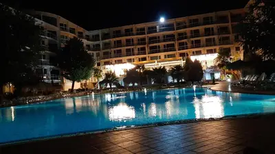 a large swimming pool in front of a building at night at Decor in Atlantis Resort&SPA by RV Apartments in Burgas City
