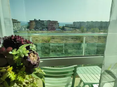 a balcony with a table and chairs and a view of a city at Прекрасен апартамент с изглед към морето Сарафово 1 in Burgas City