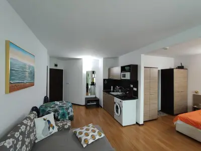 a living room with a couch and a kitchen at Прекрасен апартамент с изглед към морето Сарафово 1 in Burgas City
