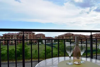 a table with a wine glass on a balcony at Bright Studio with Parking & Pool in Sveti Vlas