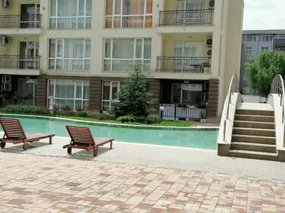two chairs sitting next to a swimming pool in a building at Cozy studio with Pool in Sunny Beach in Sunny Beach