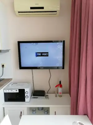a tv sitting on a wall with a curtain at Cozy studio with Pool in Sunny Beach in Sunny Beach