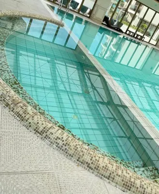 a swimming pool in a building with glass windows at Long Sunny Holiday in Shkorpilovtsi