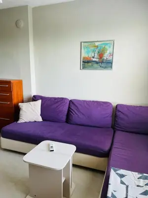 a living room with a purple couch and a table at Апартамент Морски Изглед in Burgas City