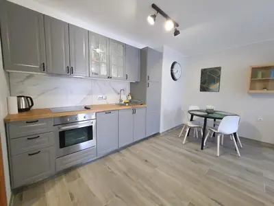 a kitchen with gray cabinets and a table with chairs at Prestige Fort Aparthotel - Private apartment-BSR in Sveti Vlas